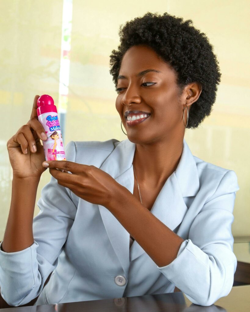 Smiling woman holding a baby care product indoors, showcasing happiness.